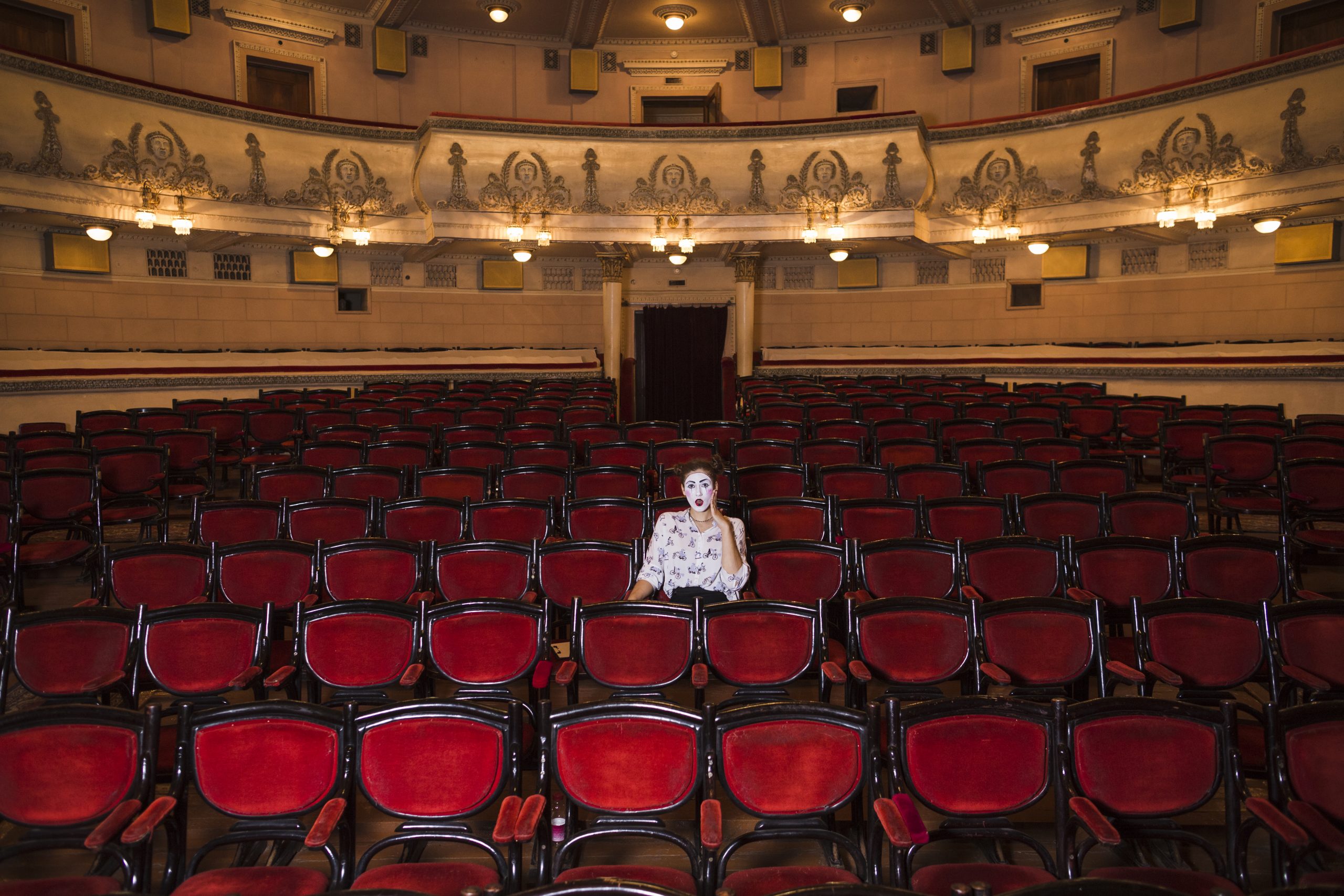 Artiste seule au milieu des fauteuils de théatre vides