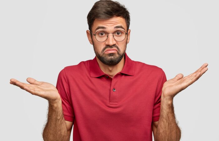 Homme avec un t-shirt rouge qui s'interroge sur ce qu'il doit faire