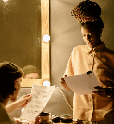 Employeur et artiste intermittent recevant et consultant son contrat CDDU dans une loge de théâtre